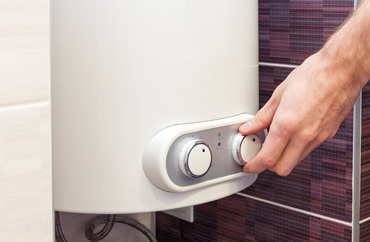 Close up picture of hand adjusting temperature on Water Heater